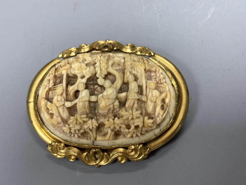 A Chinese gilt metal and ivory oval brooch, 55mm and a silver mounted clay and amberoid cheroot holder.